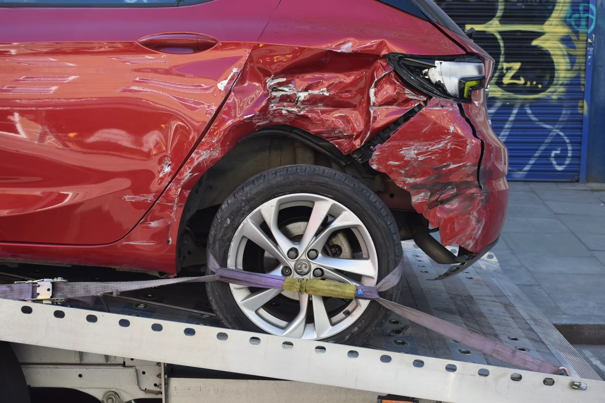 Пошкоджений у ДТП червоний автомобіль на евакуаторі — страхування в Португалії